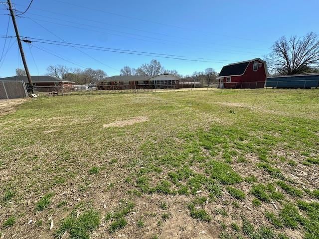 view of yard featuring an outbuilding, a barn, and fence