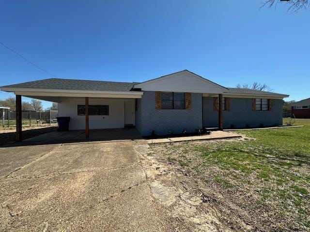single story home with a carport, concrete driveway, fence, and a front yard