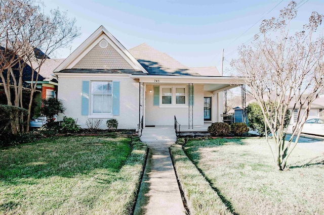 view of front of home featuring a porch, brick siding, roof with shingles, and a front yard
