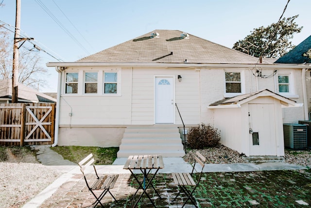 rear view of house with a gate, roof with shingles, central AC, and fence