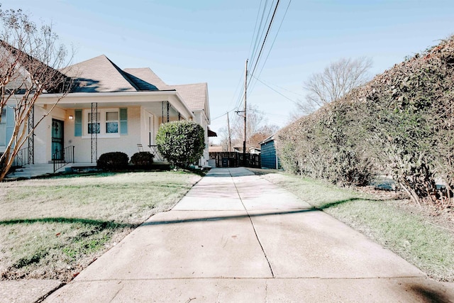 view of side of property with fence, a lawn, a porch, and a shingled roof