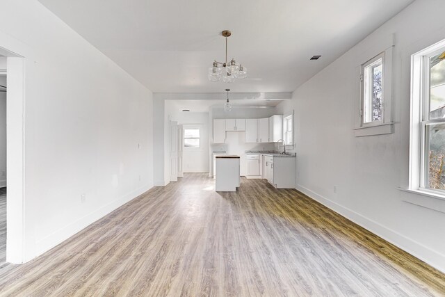 1131 Rozelle St, Memphis, TN 38106 - unfurnished living room with light wood finished floors, baseboards, a notable chandelier, and a sink