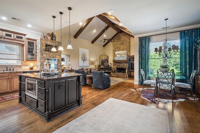 kitchen featuring dark stone countertops, a stone fireplace, visible vents, wood finished floors, and glass insert cabinets