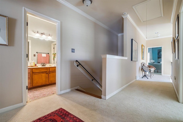 corridor featuring attic access, baseboards, an upstairs landing, light colored carpet, and crown molding