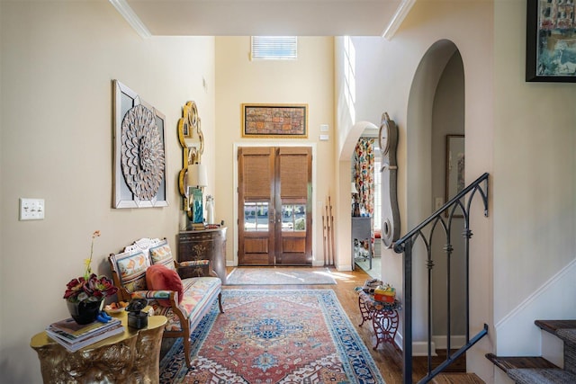 entrance foyer featuring wood finished floors, visible vents, french doors, arched walkways, and stairs