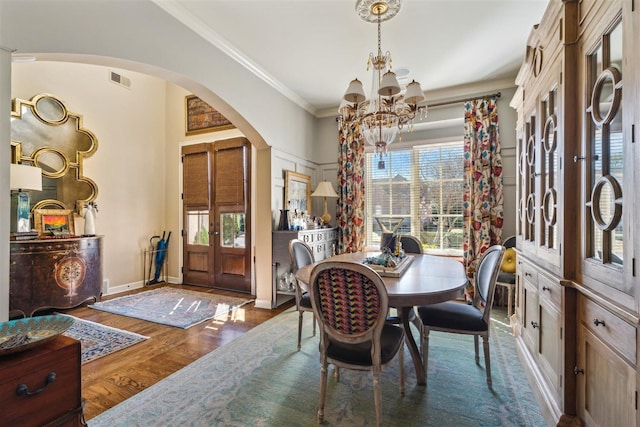 dining room with arched walkways, a chandelier, a healthy amount of sunlight, and crown molding