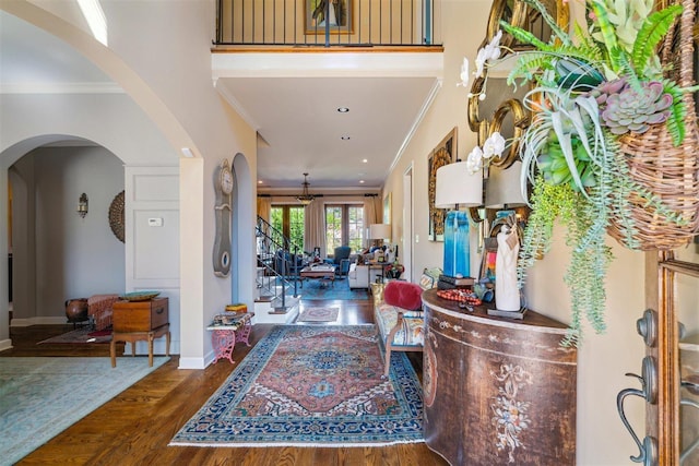 foyer entrance featuring arched walkways, baseboards, recessed lighting, wood finished floors, and ornamental molding