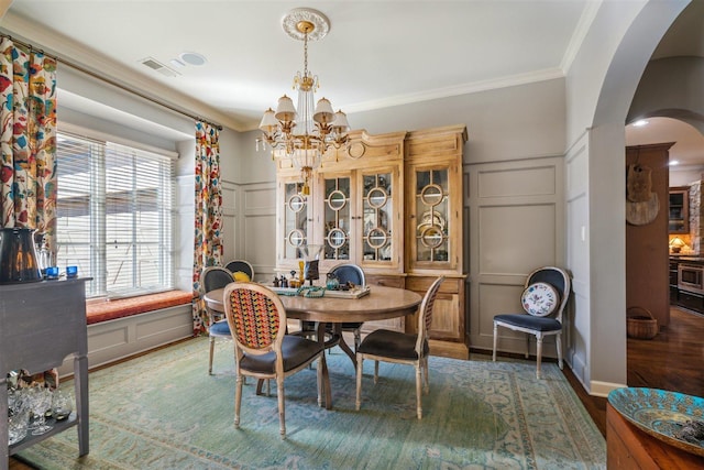 dining space with arched walkways, a decorative wall, ornamental molding, and visible vents