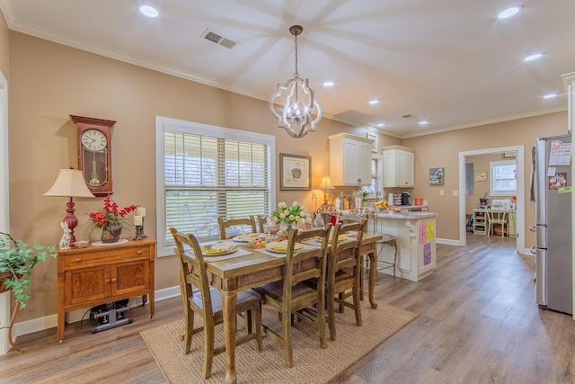 dining area featuring ornamental molding, visible vents, a chandelier, and light wood-style floors