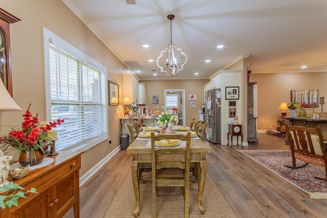 dining room featuring baseboards, ornamental molding, light wood-style flooring, and a notable chandelier