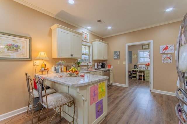 kitchen featuring a kitchen breakfast bar, stainless steel appliances, visible vents, white cabinets, and wood finished floors