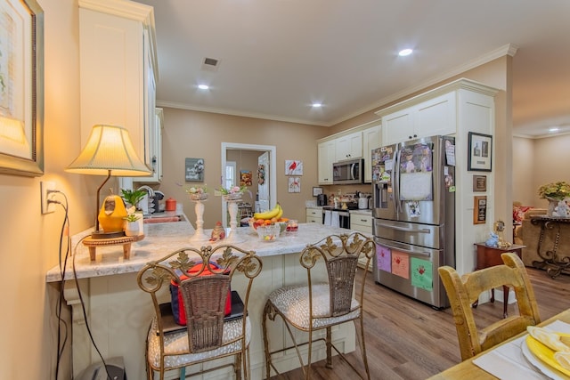kitchen with white cabinetry, crown molding, stainless steel appliances, and a peninsula