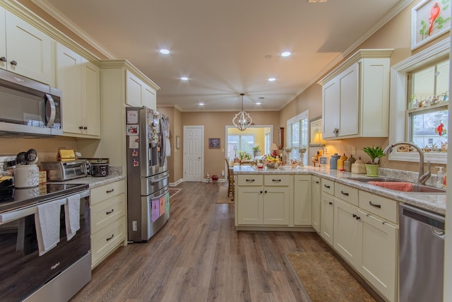 kitchen featuring crown molding, a sink, a peninsula, and appliances with stainless steel finishes