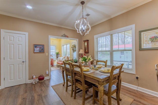 dining room with a wealth of natural light, a notable chandelier, crown molding, and wood finished floors