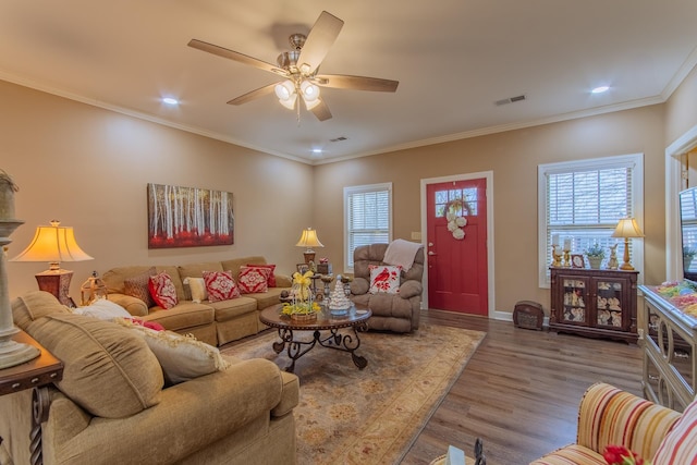 living area featuring ornamental molding, visible vents, plenty of natural light, and wood finished floors