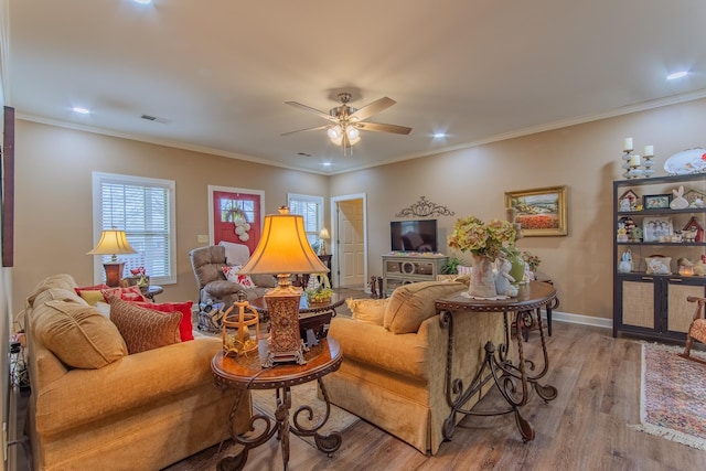 living room featuring crown molding, baseboards, visible vents, a ceiling fan, and wood finished floors
