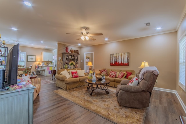 living room with a ceiling fan, wood finished floors, visible vents, ornamental molding, and recessed lighting