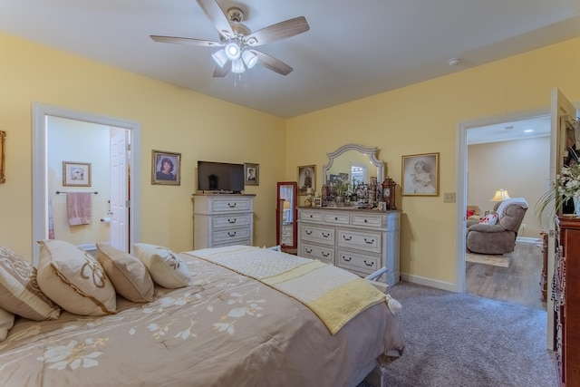 carpeted bedroom featuring ensuite bath, baseboards, and ceiling fan