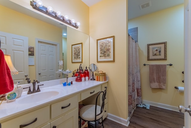 bathroom with vanity, a shower with shower curtain, baseboards, visible vents, and wood finished floors
