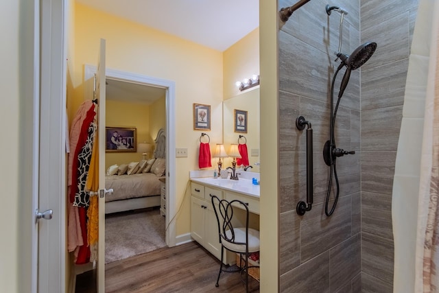ensuite bathroom with vanity, ensuite bathroom, a tile shower, and wood finished floors