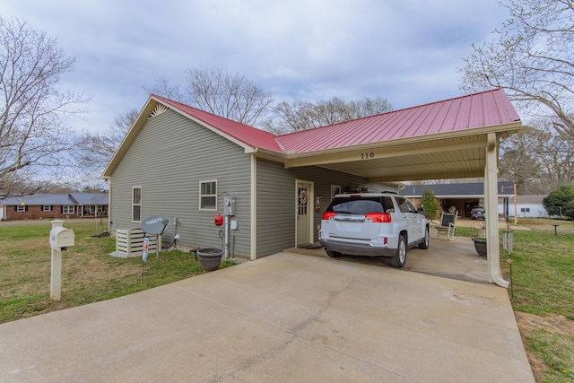view of side of property with a yard, metal roof, a carport, and concrete driveway
