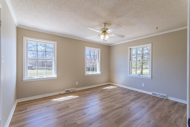 unfurnished room with a wealth of natural light, visible vents, wood finished floors, and ceiling fan