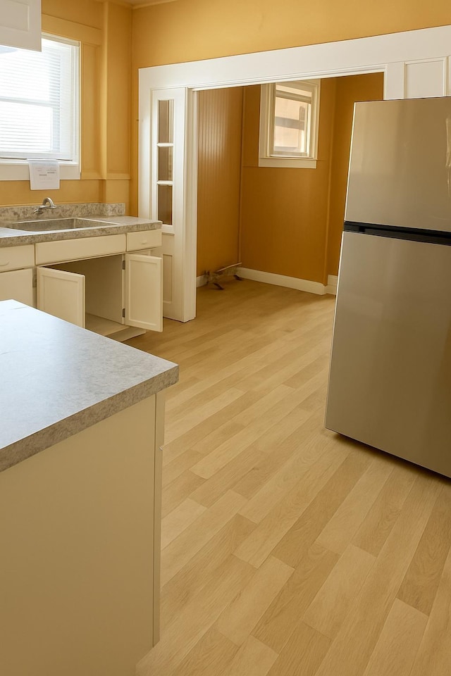 1535 Southern Ave, Memphis, TN 38114 - kitchen with freestanding refrigerator, light countertops, white cabinets, light wood finished floors, and plenty of natural light