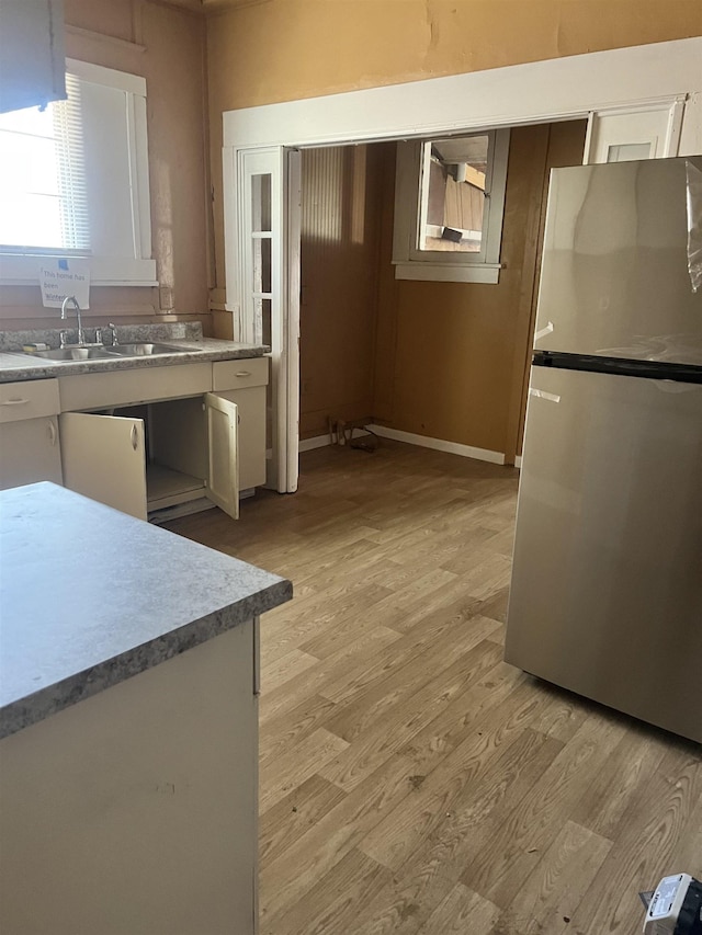 1535 Southern Ave, Memphis, TN 38114 - kitchen featuring freestanding refrigerator, light wood-style floors, a sink, light countertops, and white cabinetry