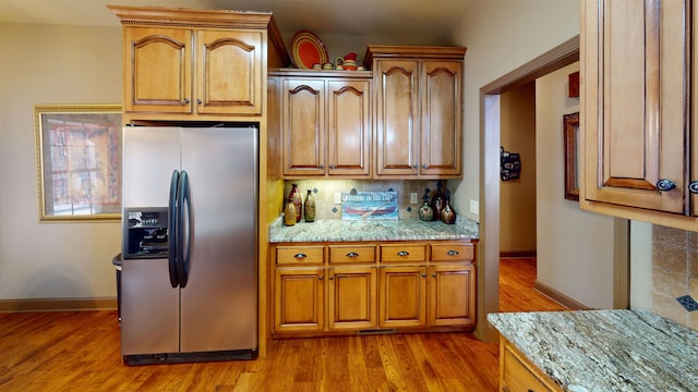100 Carefree Ln, Counce, TN 38326 - kitchen featuring tasteful backsplash, brown cabinetry, light wood finished floors, baseboards, and stainless steel refrigerator with ice dispenser