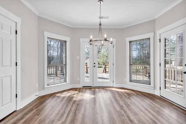 unfurnished dining area featuring crown molding, baseboards, visible vents, a notable chandelier, and wood finished floors