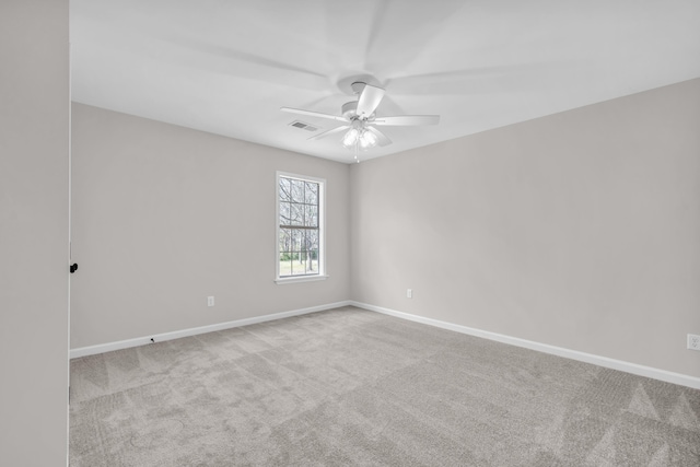 carpeted spare room with baseboards, visible vents, and ceiling fan