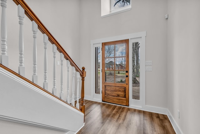 foyer featuring baseboards, a high ceiling, wood finished floors, and stairway