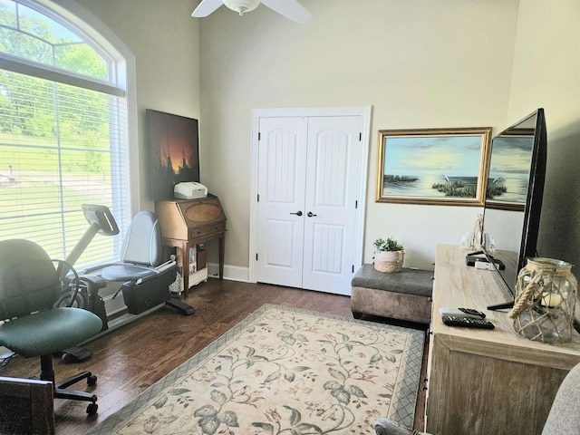 office area featuring a towering ceiling, baseboards, ceiling fan, and dark wood finished floors