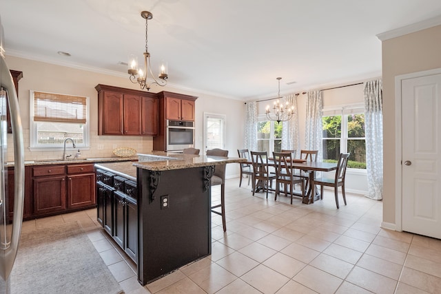 kitchen with crown molding, a breakfast bar, stainless steel oven, a sink, and a notable chandelier