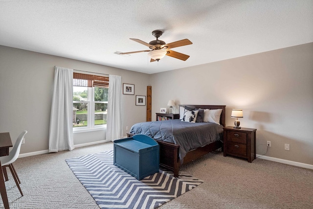 bedroom featuring baseboards, a textured ceiling, a ceiling fan, and light colored carpet