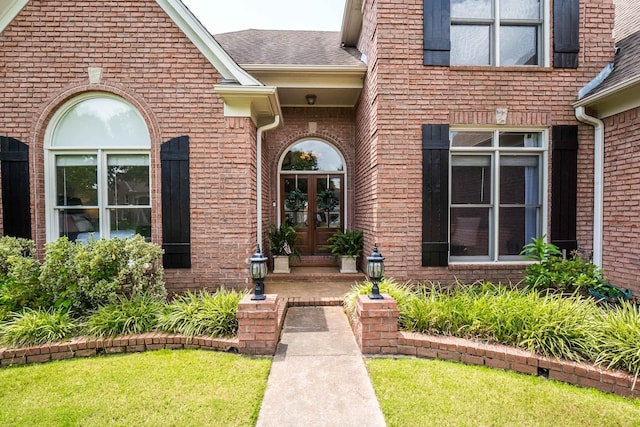 entrance to property featuring brick siding, a shingled roof, and french doors