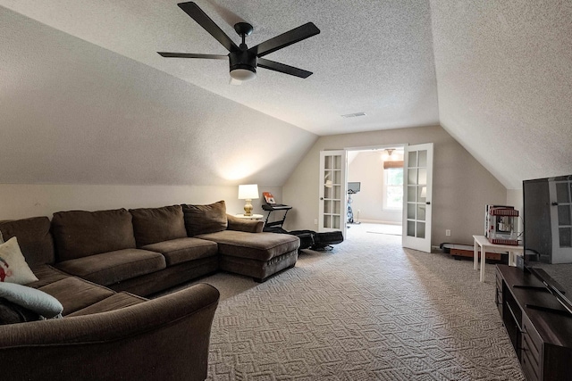 carpeted living room with french doors, a textured ceiling, lofted ceiling, visible vents, and ceiling fan