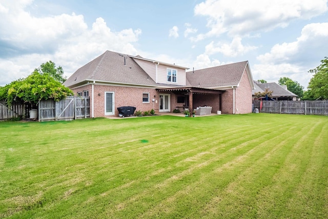 back of property featuring a patio, a fenced backyard, brick siding, roof with shingles, and a lawn