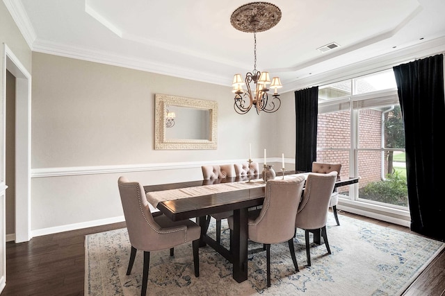 dining space with a tray ceiling, wood finished floors, and an inviting chandelier