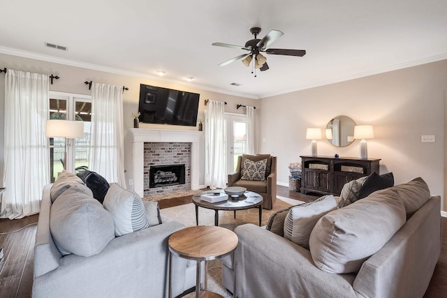 living room with dark wood-style flooring, a fireplace, visible vents, and a ceiling fan