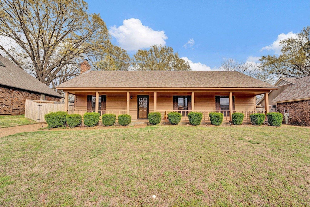 ranch-style house featuring a front lawn, a chimney, and covered porch