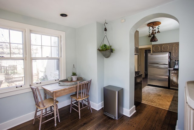 dining room with baseboards, arched walkways, and dark wood-type flooring