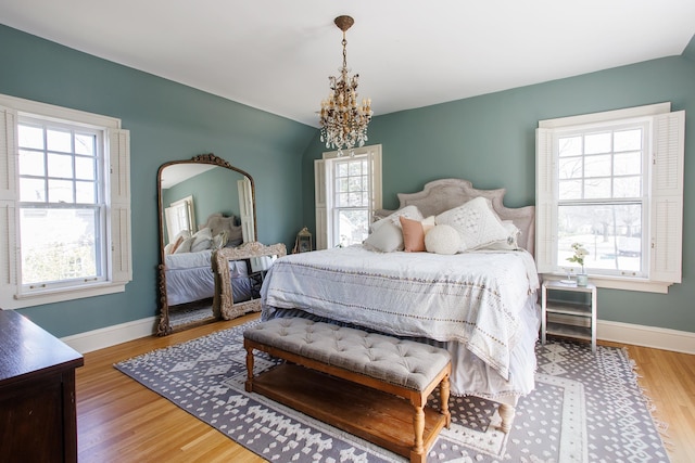 bedroom featuring baseboards, a chandelier, and wood finished floors