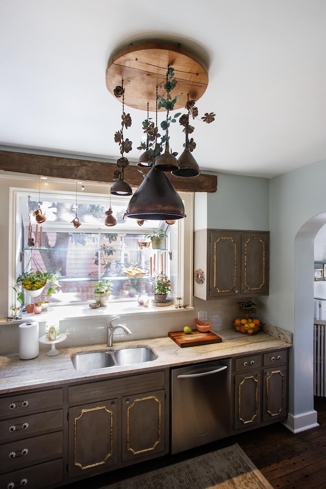 kitchen with tasteful backsplash, stainless steel dishwasher, a sink, arched walkways, and dark wood-style floors