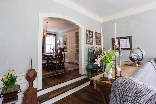 interior space with a notable chandelier, wood finished floors, arched walkways, and ornamental molding