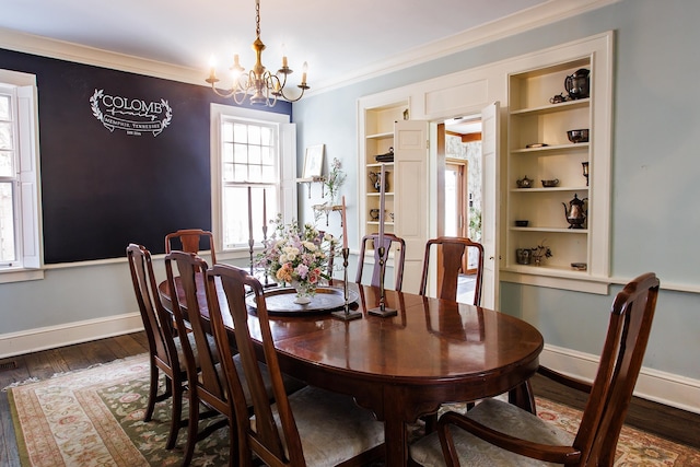 dining room with a notable chandelier, dark wood-type flooring, baseboards, and crown molding
