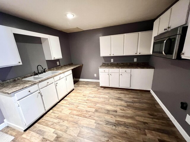 29 Wardlow St, Gates, TN 38037 - kitchen with white cabinets, light wood-style flooring, a sink, and stainless steel microwave