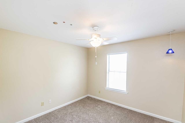 carpeted empty room with a ceiling fan and baseboards
