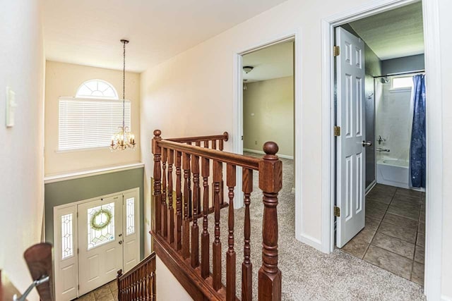 stairway with a chandelier, carpet, tile patterned flooring, and baseboards