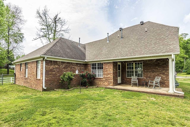 rear view of house with fence, a lawn, a shingled roof, and brick siding
